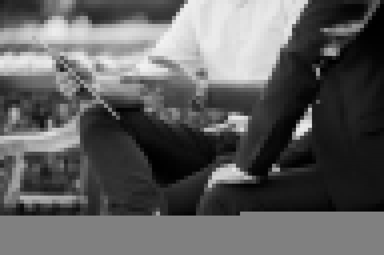 Two business men sitting on a park bench looking at an iPad
